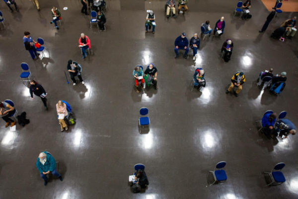 As seen from above, people sit in chairs spaced six feet apart
