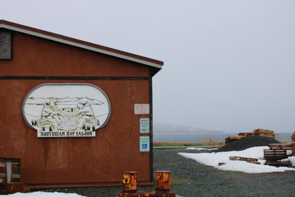 A redish wooden uilding with a sign that says "norwegian rat"  in a foggy location