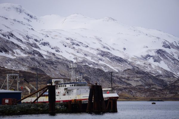 A boat at dock in front of a snow-covered montain