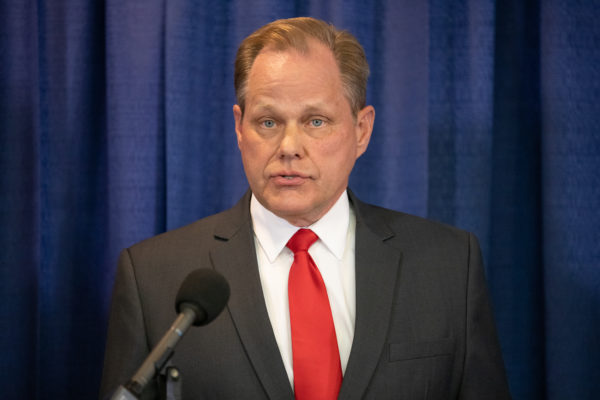 man with red tie speaks at a podium