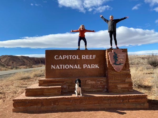 two children stand on a national park sign