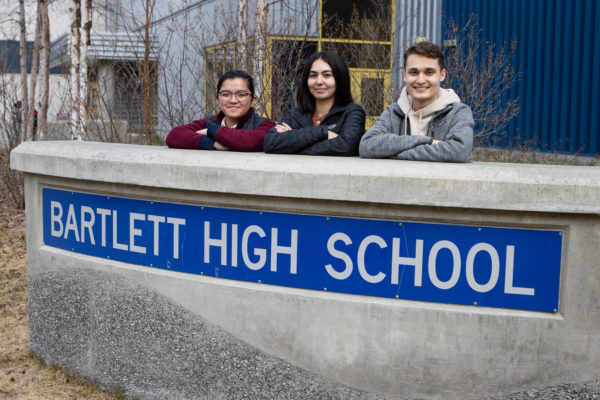 three highschool students pose in front of sign that reads: bartlett high school