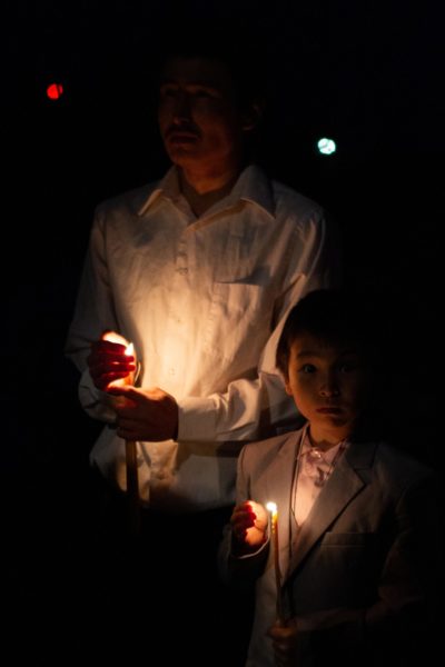 A person holds a candle with a child next to him