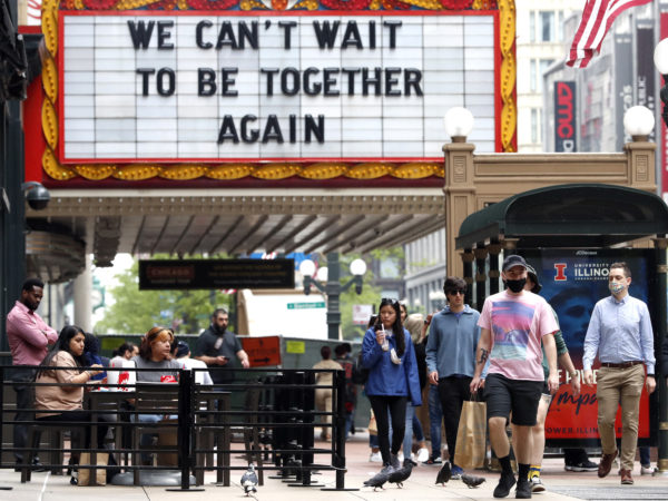People walk under a big sign that says "We can't wait to be together again." 