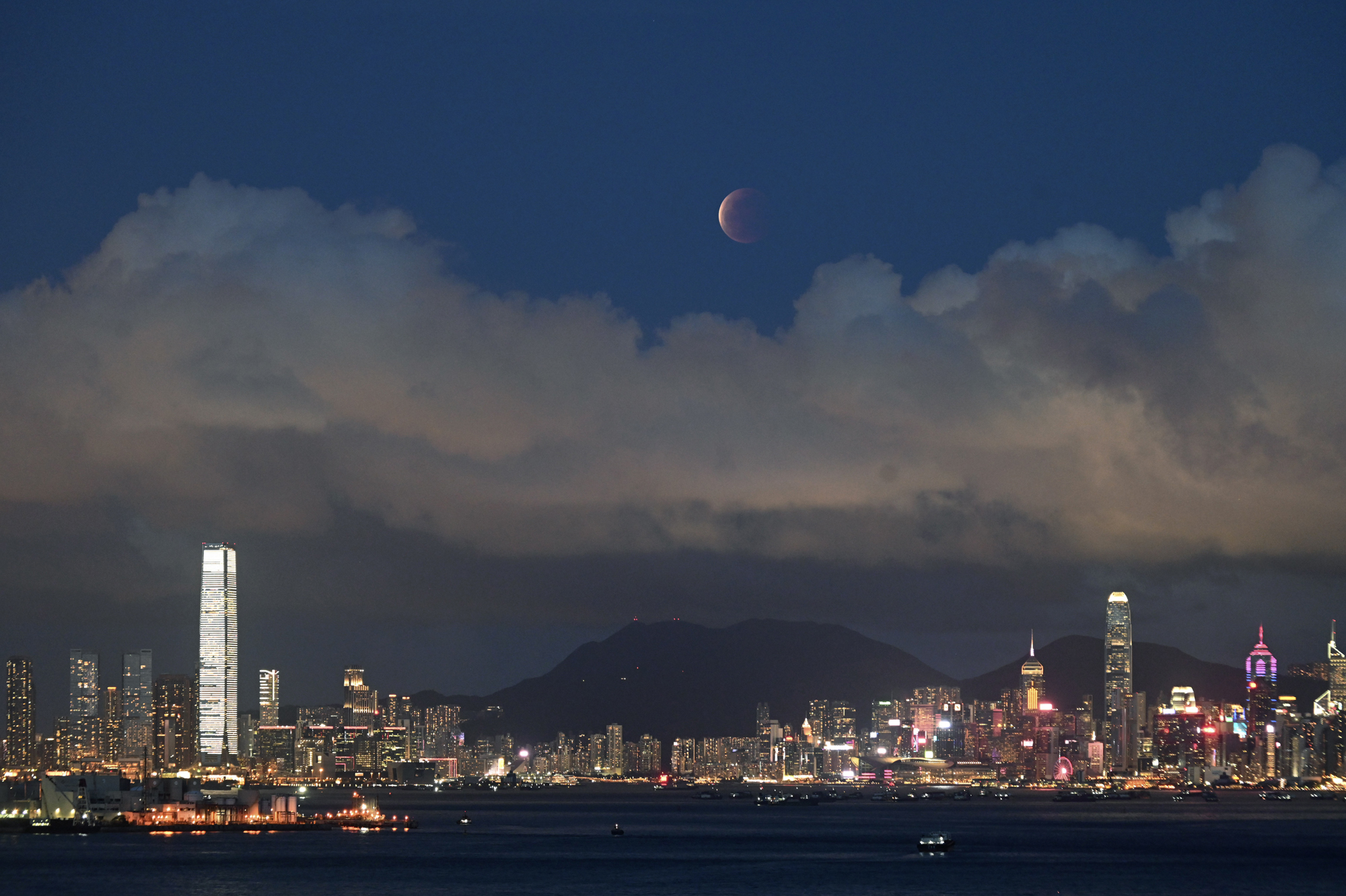 The moon rises over Victoria Harbour in Hong Kong on Wednesday