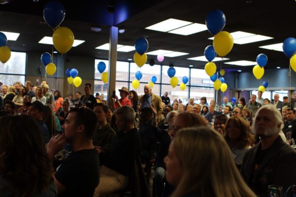 A room filled with people  an blue and yellow baloons