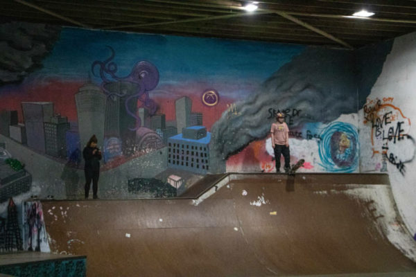 A woman descends a half pipe with graffittti on the wall behind her