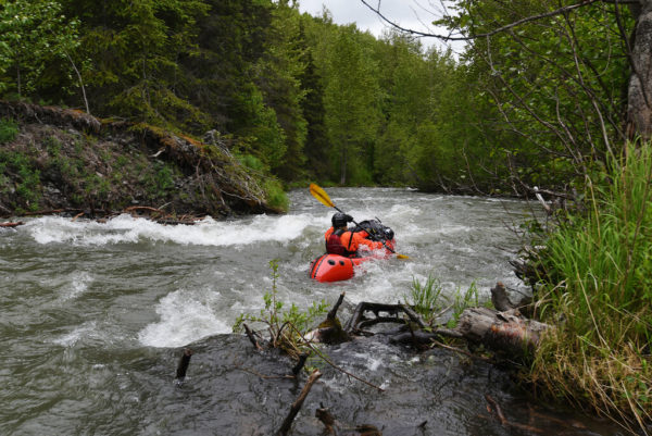 A red packraft in a creek 