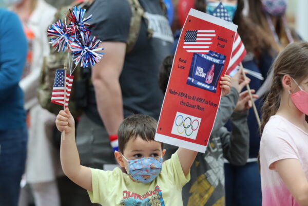A young boy holds an american flag and a poster