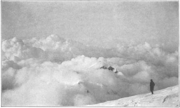 A person on a mountain above some clouds in a black and white photo