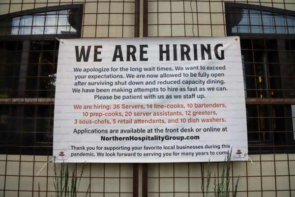 a sign posted outside a restaurant reads "we are hiring"