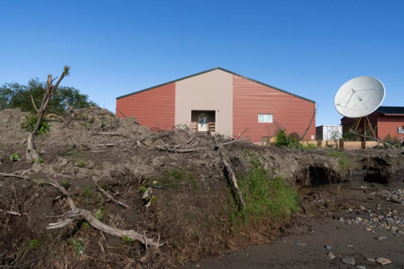 A red building on top of an eroding river bank