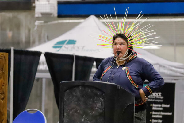 a person on stage performs while wearing a headdress made of neon zip ties