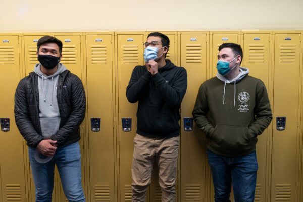 Three students in front of yellow lockers
