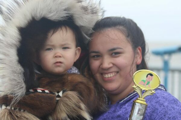 A woman in a kuspuk with a baby in a fur ruffed parka