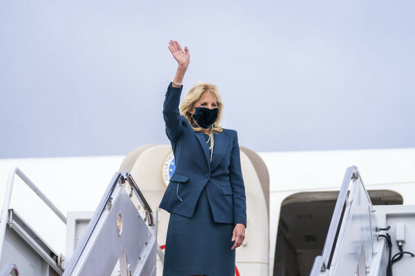 A blond woman waves while getting off a plane