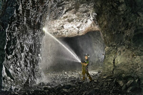 A worker sprays the wall of a rock tunner
