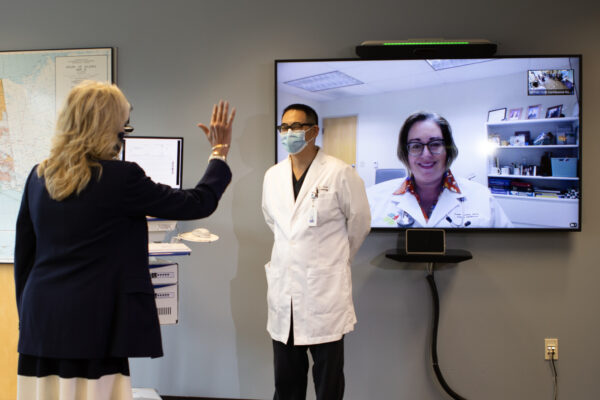 A woman waves at another woman who appears on a screen.