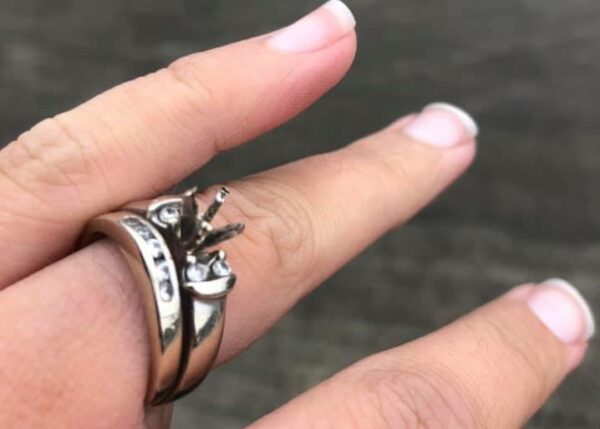 An engagement ring on a finger is missing the diamond.