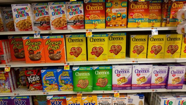 Grocery store shelves filled with boxes of a variety of cereal brands.