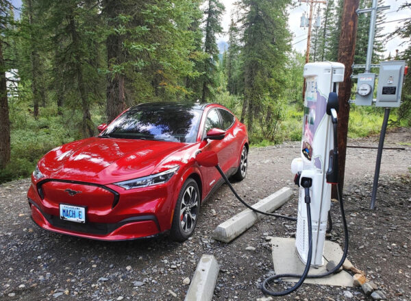 A red sports car is plugged in to a recharge station.