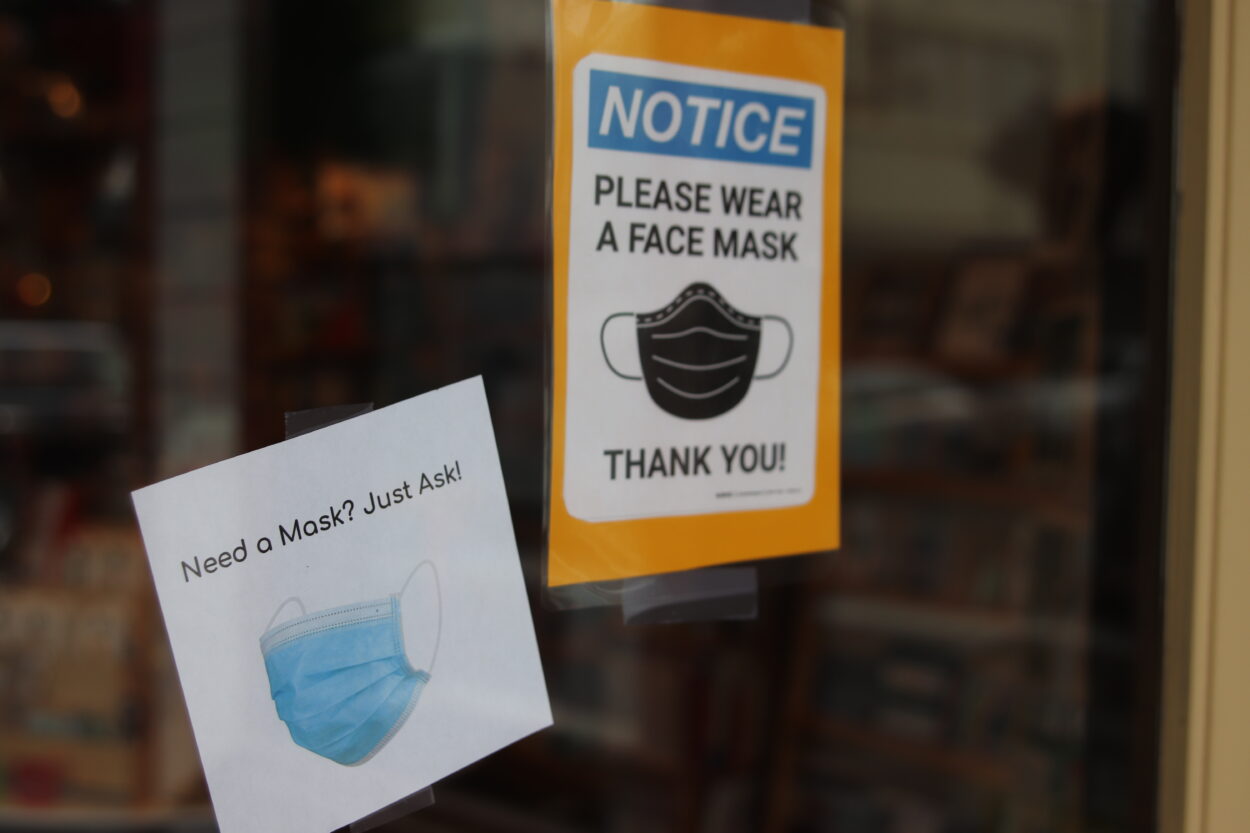 Two signs on a glass door ask customers to wear a face mask.
