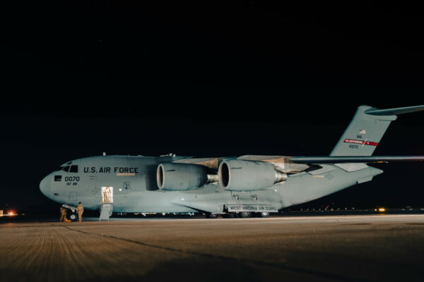 A large plane is parked on a runway at night.