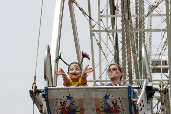 Girl with face paint and pigtails with her mom on a ferris wheel
