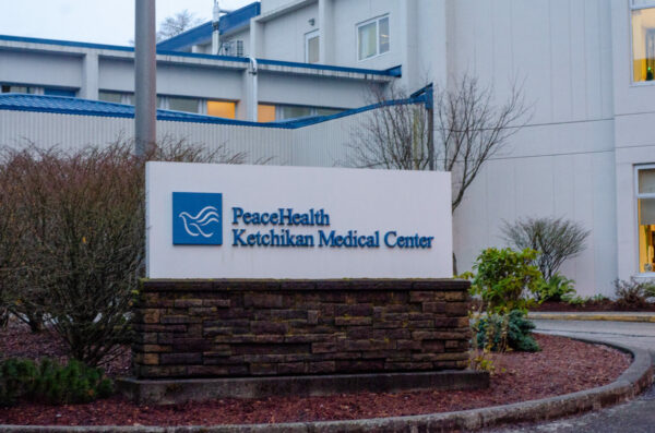 A white and blue sign outside of a multi-story white and blue medical building.