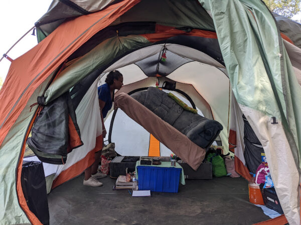 A woman lifts up a bed inside a clean tents
