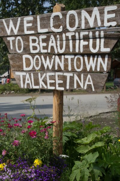 A wooden sign reads "Welcome to beautiful downtown Talkeetna."