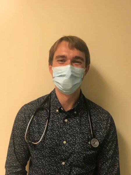 A portrait of a man wearing a face mask, with a stethoscope around his neck.