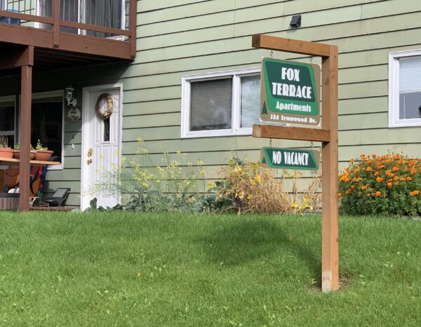 A sign reads "Fox Terrance Apartments: No vacancy" outside of a green-colored building.