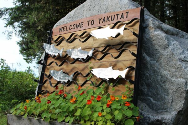 An outdoor sign that says Yakutat with fish.