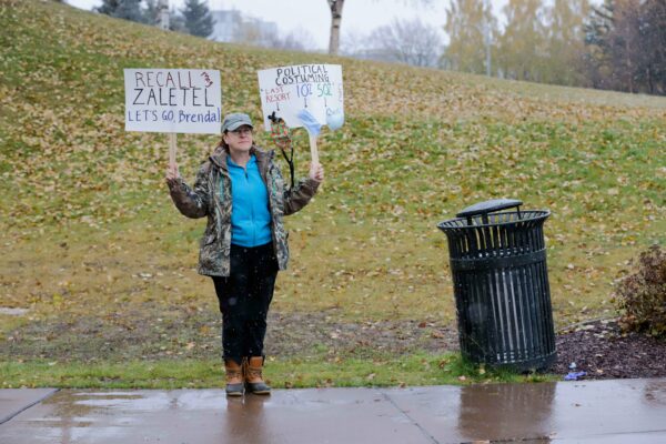 A woman holds a sign calling for Assembly member Meg Zaletel's recall.