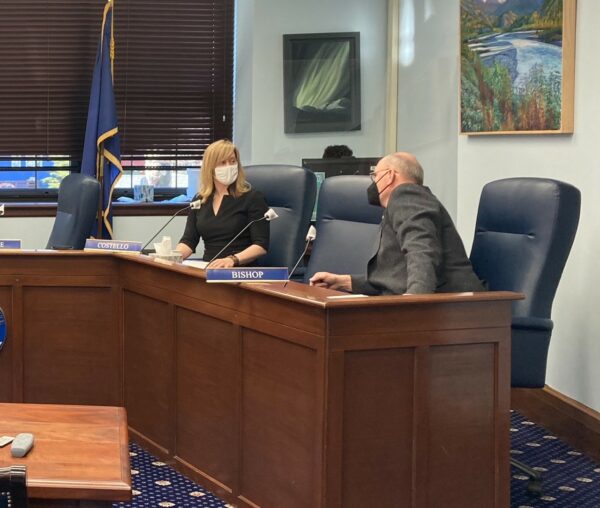 Two legislators in a room with masks on.