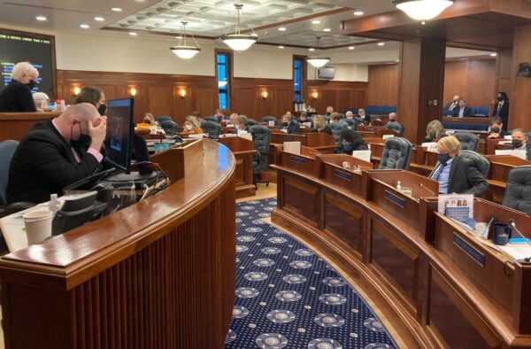 people in wooden desks on the floor of the Alaska House of Representatives
