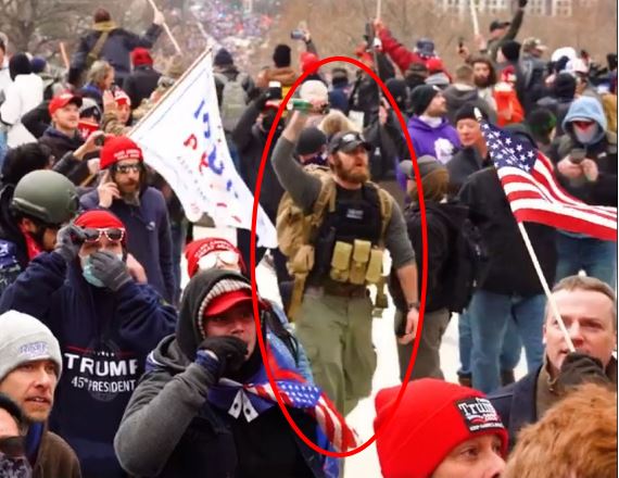 A red circle around a man in a group of people, some with Trump signs or American flags.