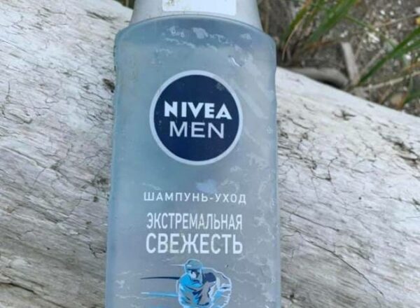 A NIVEA men shampoo bottle rests on a log.