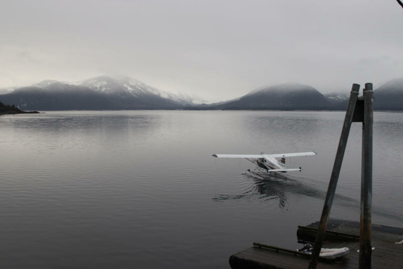 A float plane sits on the water in an overcast day.