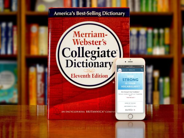 A red dictionary and phone with the dictionary app sit on a table.