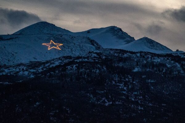 A light-up star on a mountainside.