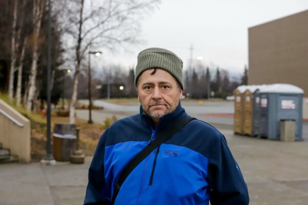 a person with a hat on poses for a photo outside a shelter