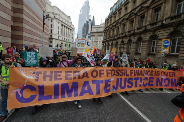 Protestors with a banner that says "the era of fossil fuel finance is over. Climate Justice now."