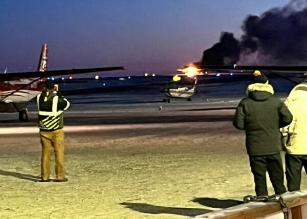 People look on as a plane is on fire.