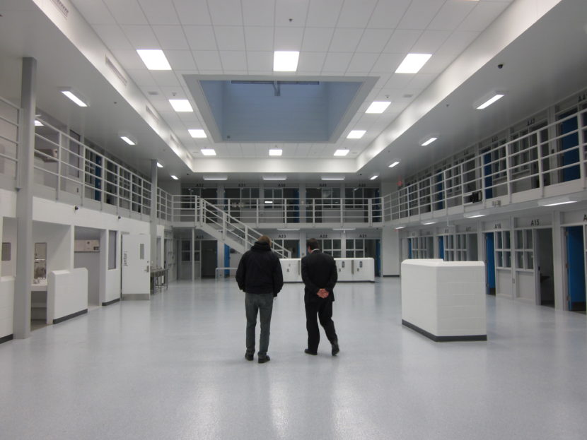 Two people walk through a prison.