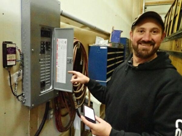 A man points to an electrical panel.