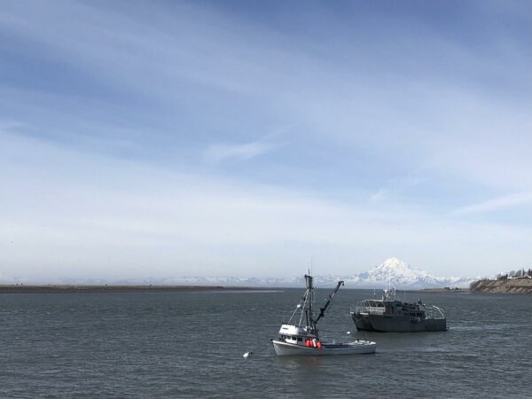 Two fishing boats with a tall snow covered mountain in the distance