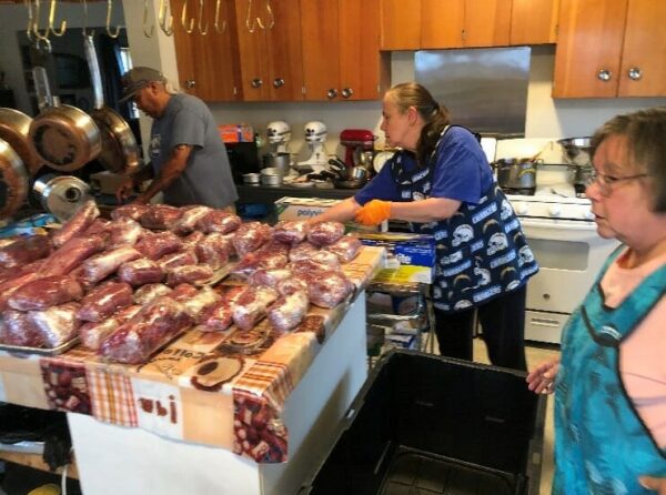 People cut up meat in a kitchen.