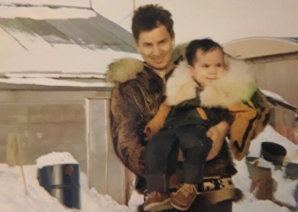 A man in a winter jacket holds a baby in a winter jacket.